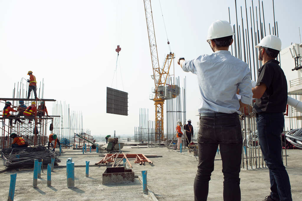 Gestor em campo de obra coordenando e avaliando projeto conduzido com medotologia BIM